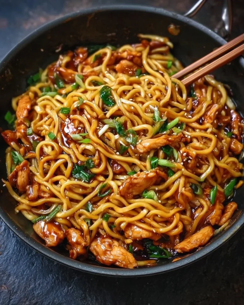 Plate of sticky garlic chicken noodles with vibrant veggies and herbs